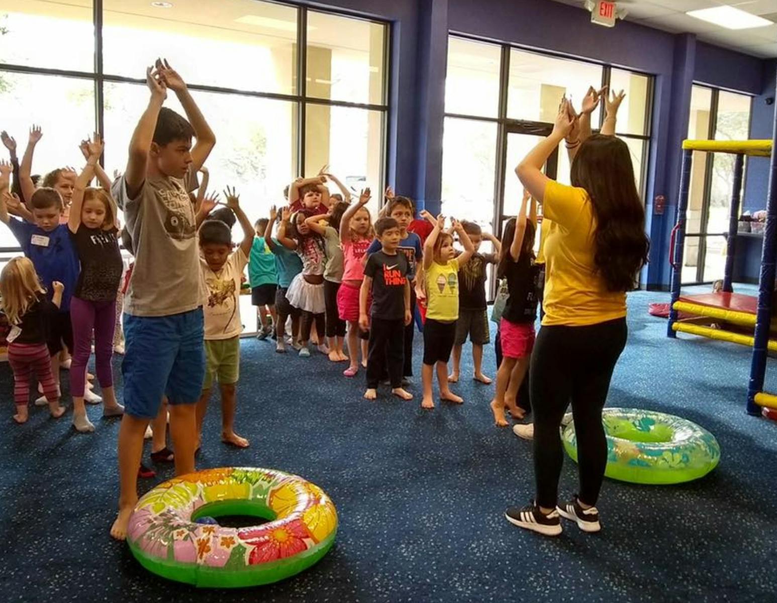 Adult and children with hands raised in a room