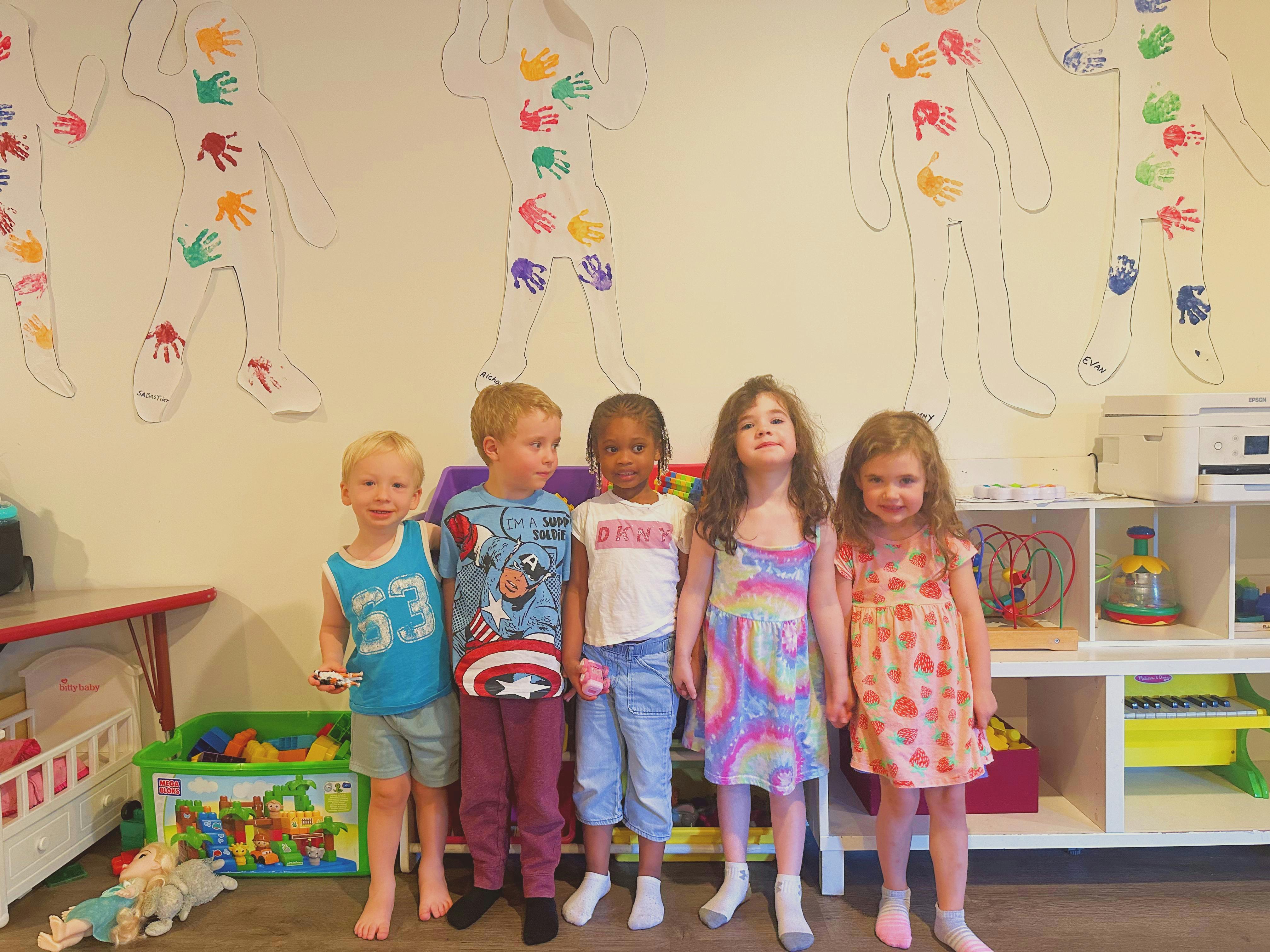 Five children standing in a classroom