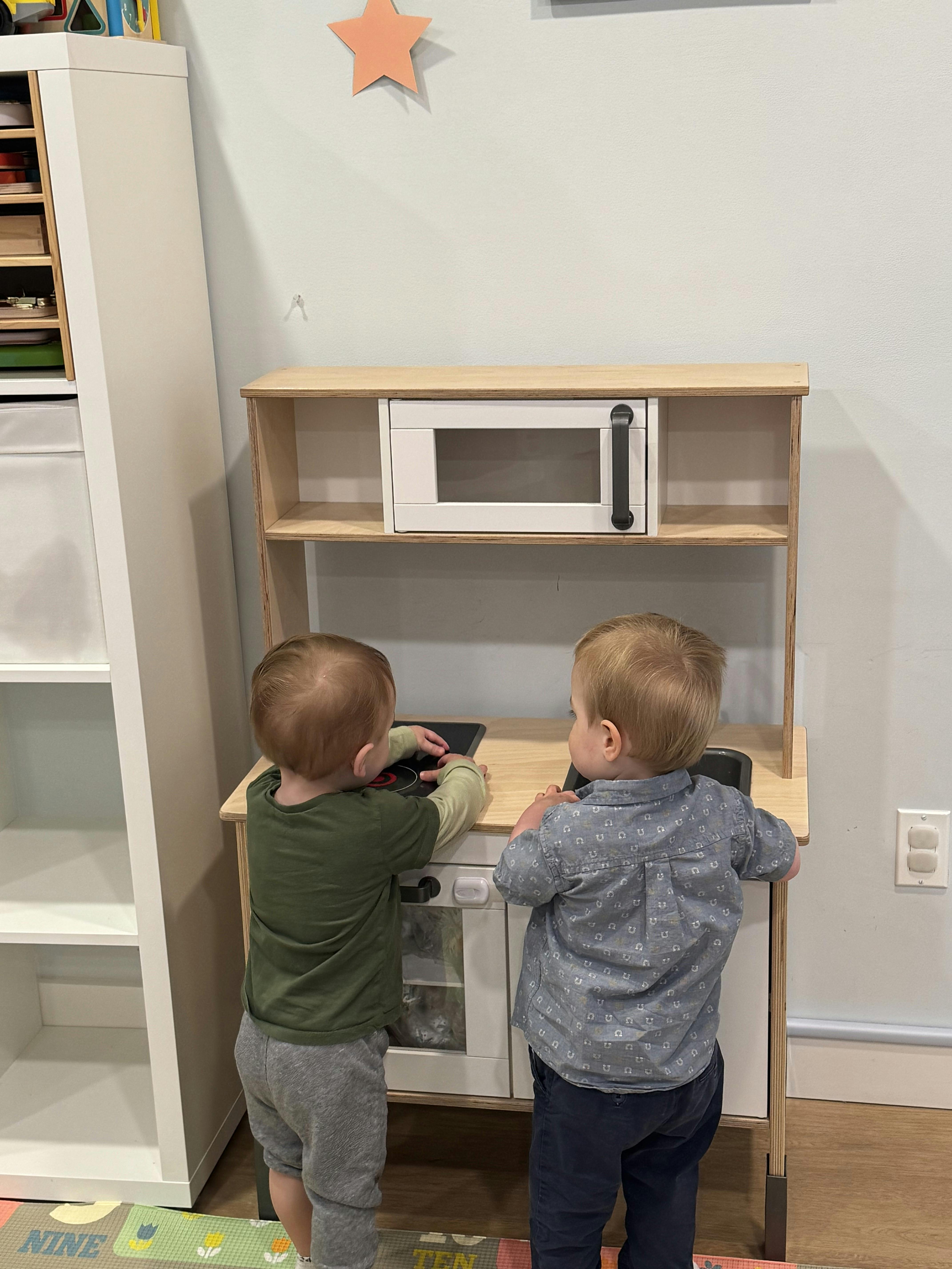 Two children playing with a toy kitchen