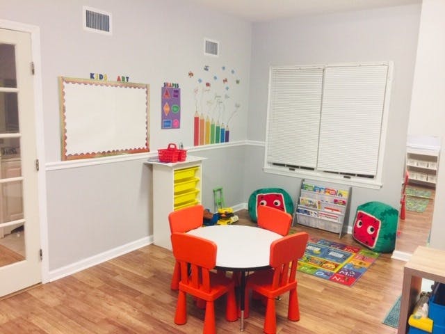 Classroom with small red chairs and white table, whiteboards, and colorful decorations