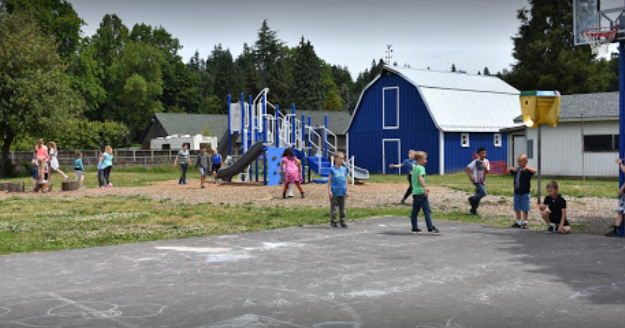 Children playing on a playground with a blue barn in the background