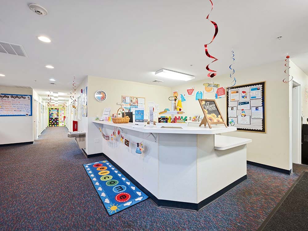 Reception desk in a daycare or preschool hallway with a welcome mat