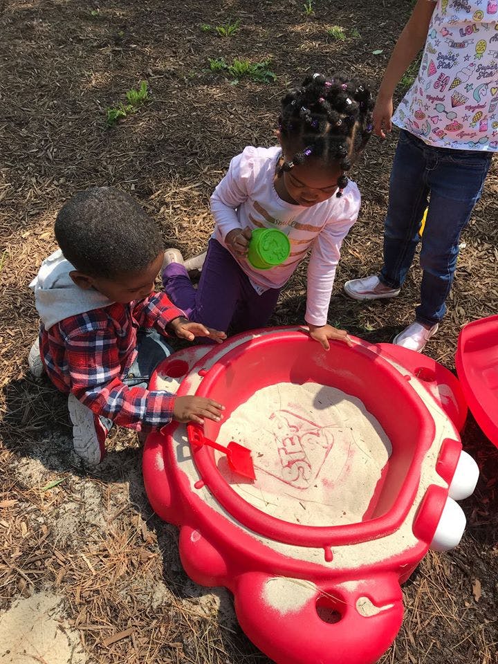 Children playing in a red sandbox