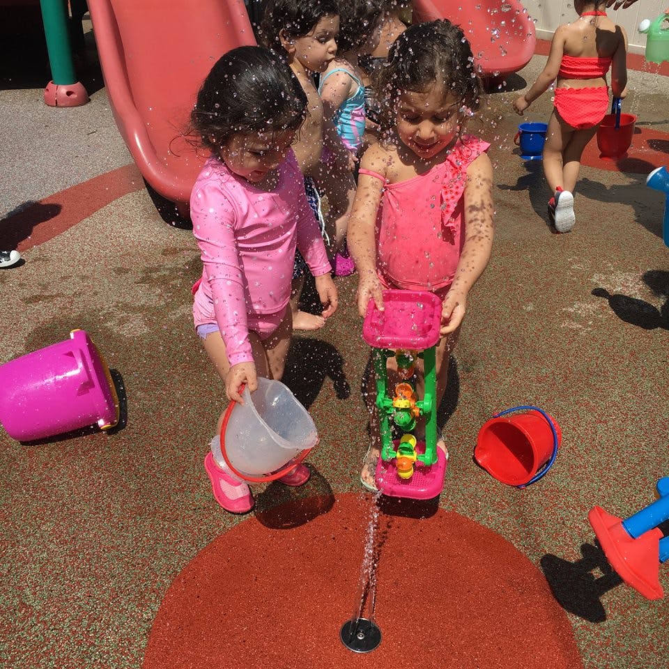 Two children playing with water toys at a splash pad