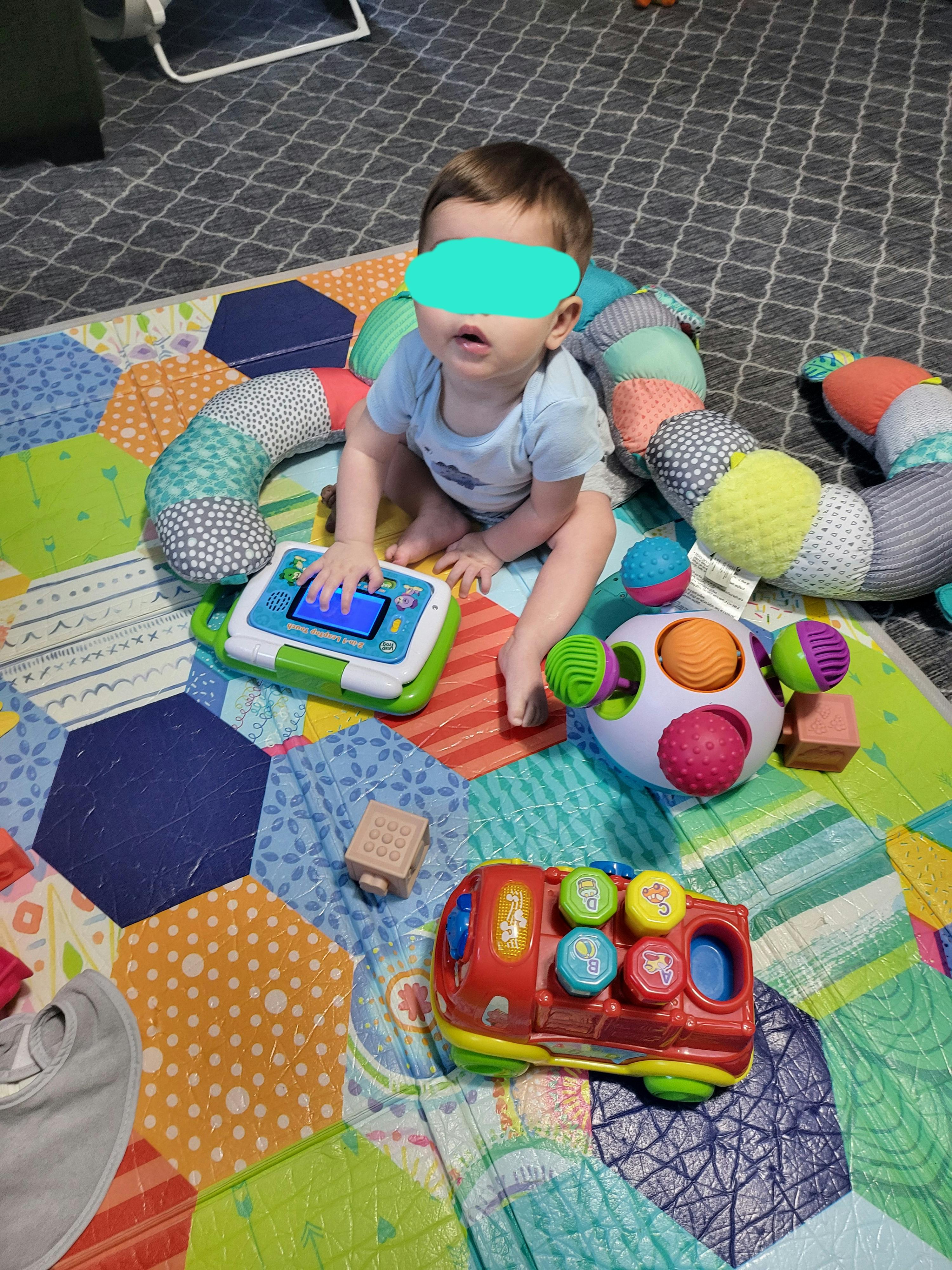 Child sitting on a playmat, playing with toys