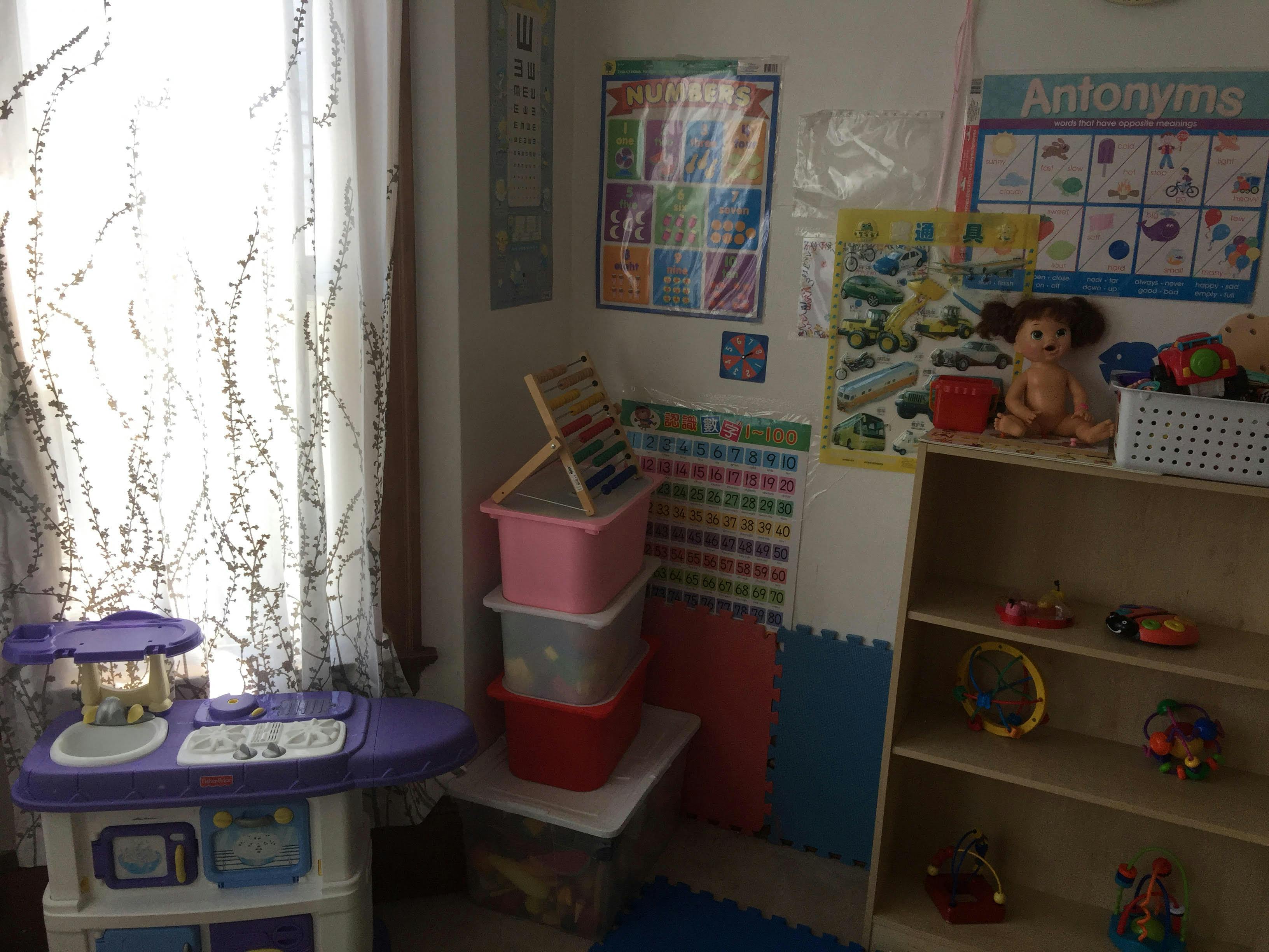Playroom with toys, storage bins, and educational posters on the wall