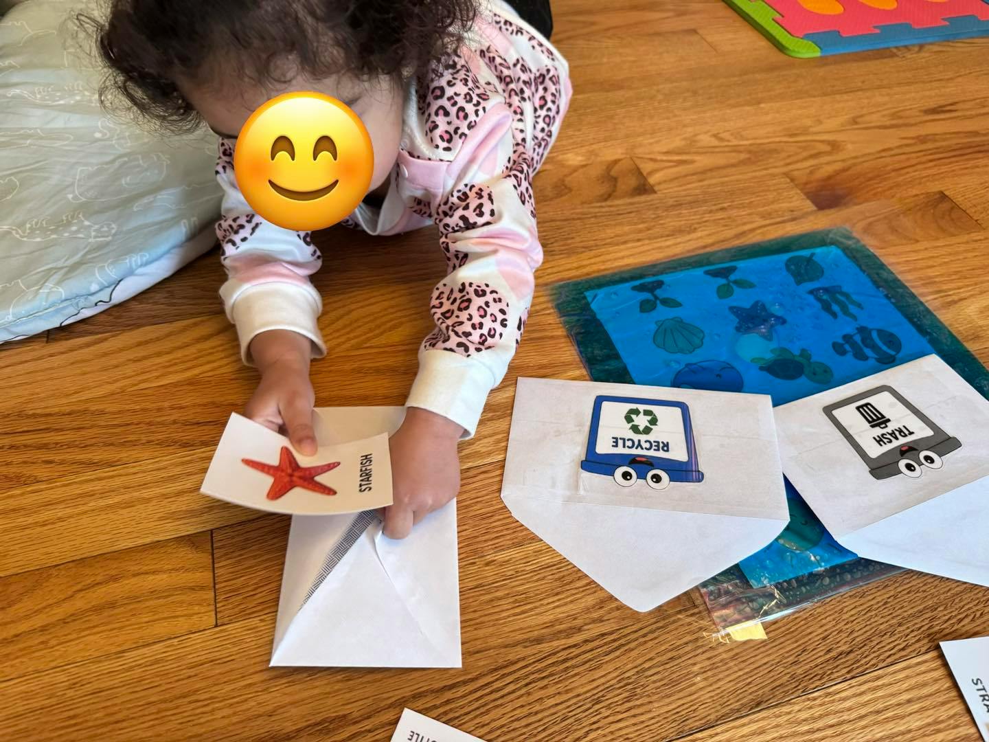 Child lying on floor, holding a flashcard with a starfish
