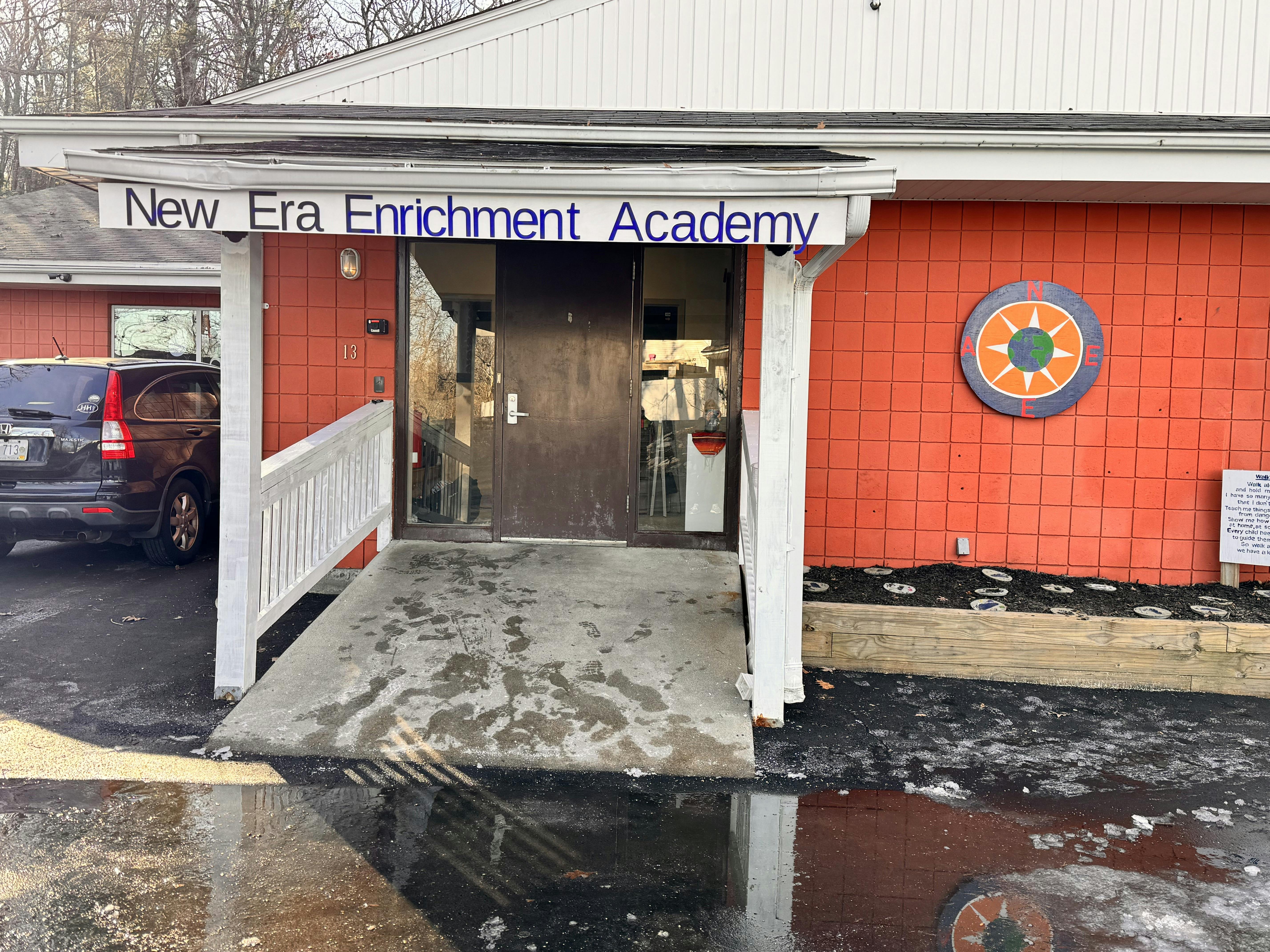Building entrance with a sign reading "New Era Enrichment Academy"