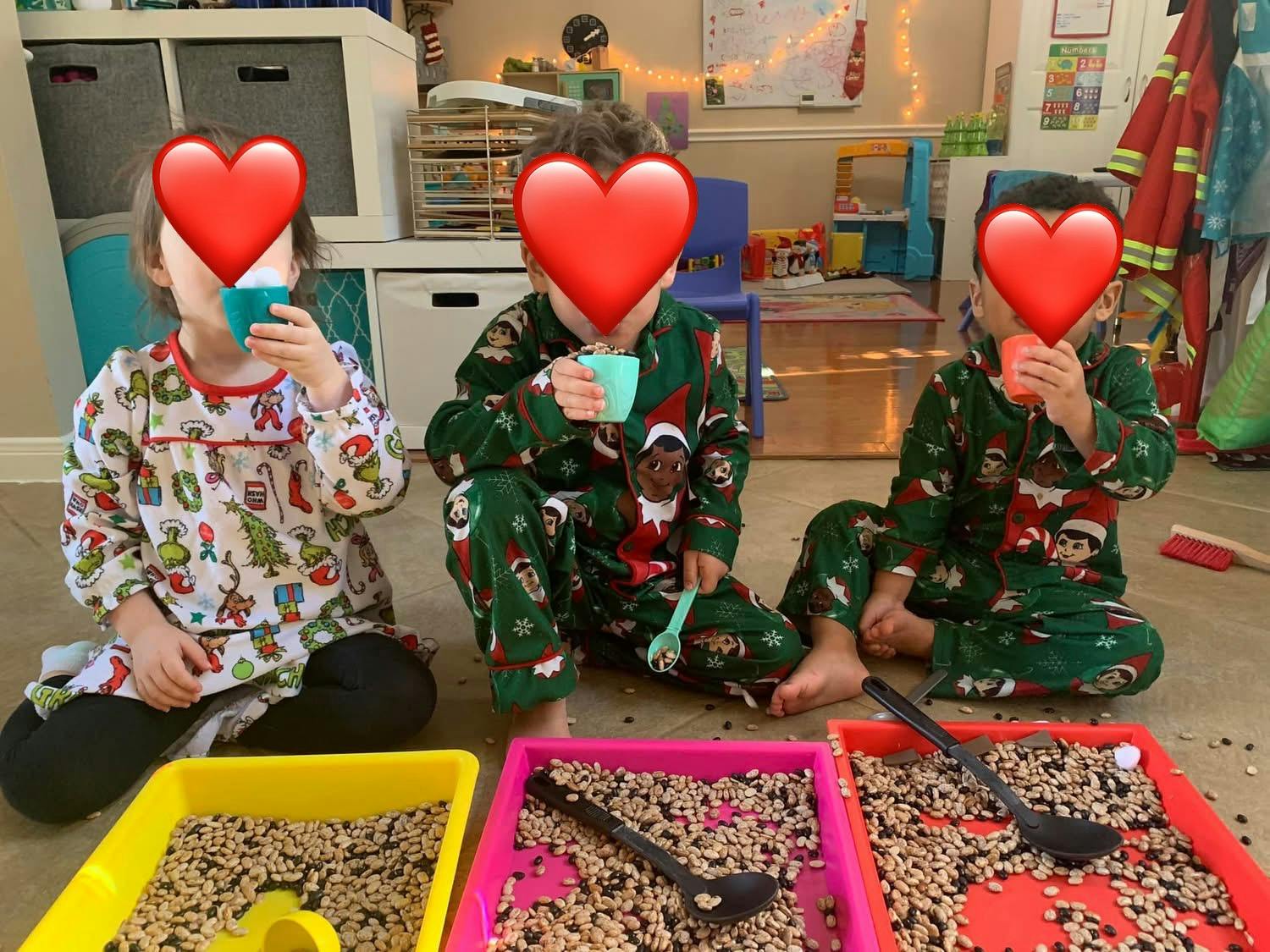 Three children in pajamas playing with sensory bins