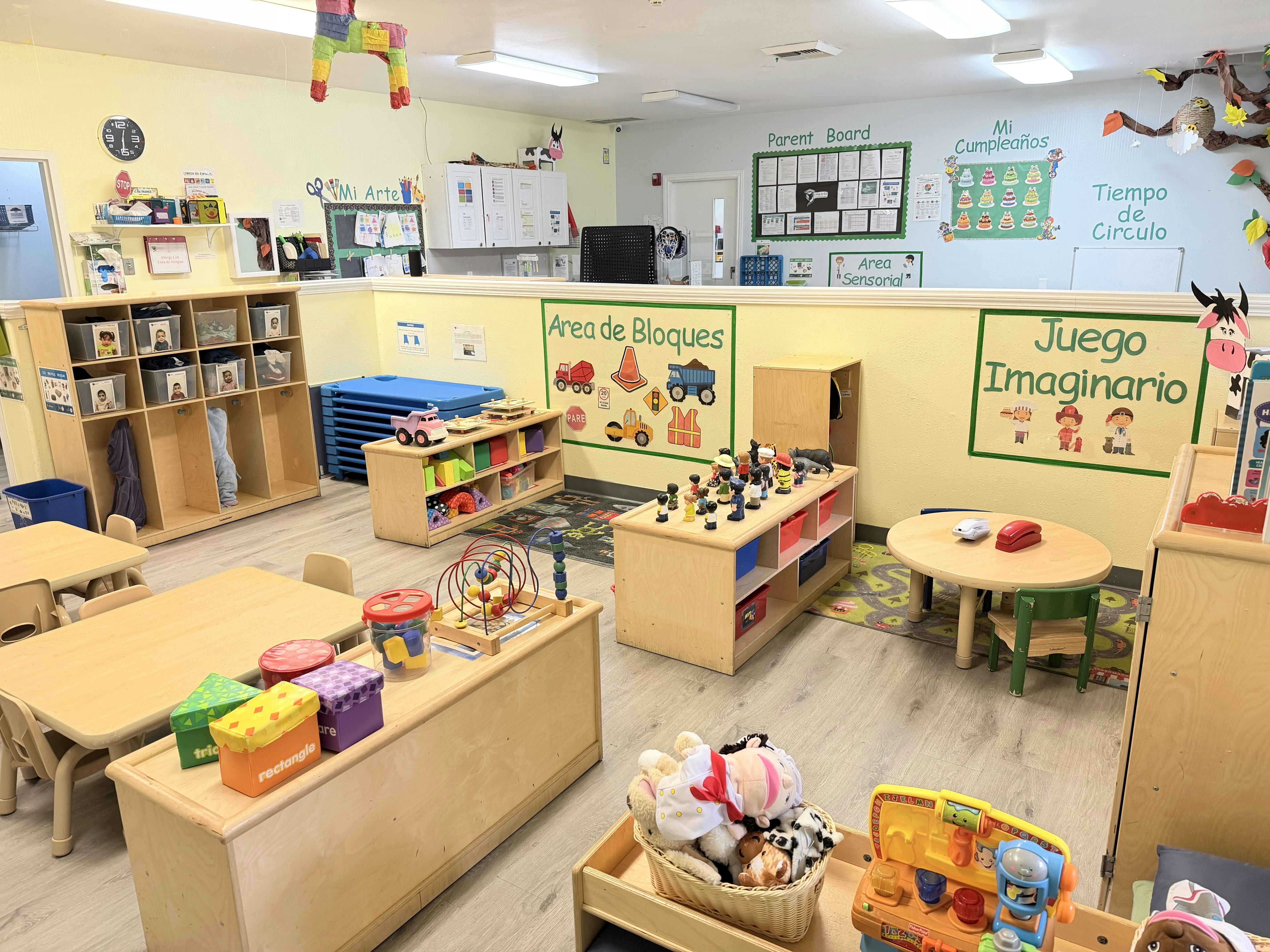 Classroom filled with wooden furniture, toys, and educational wall signs