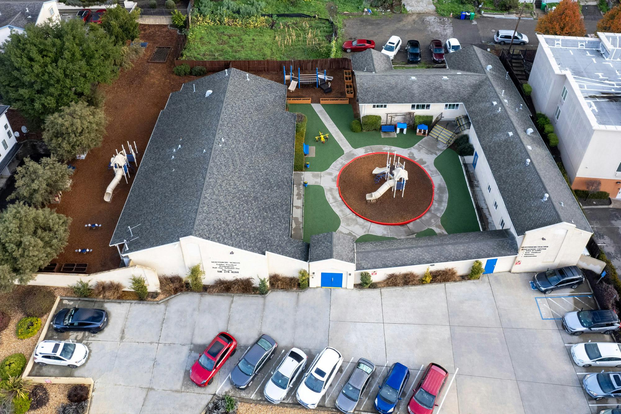 Aerial view of a school building with a playground and parking lot