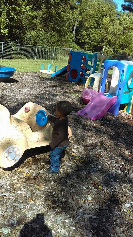 Child playing on a playground with a toy car