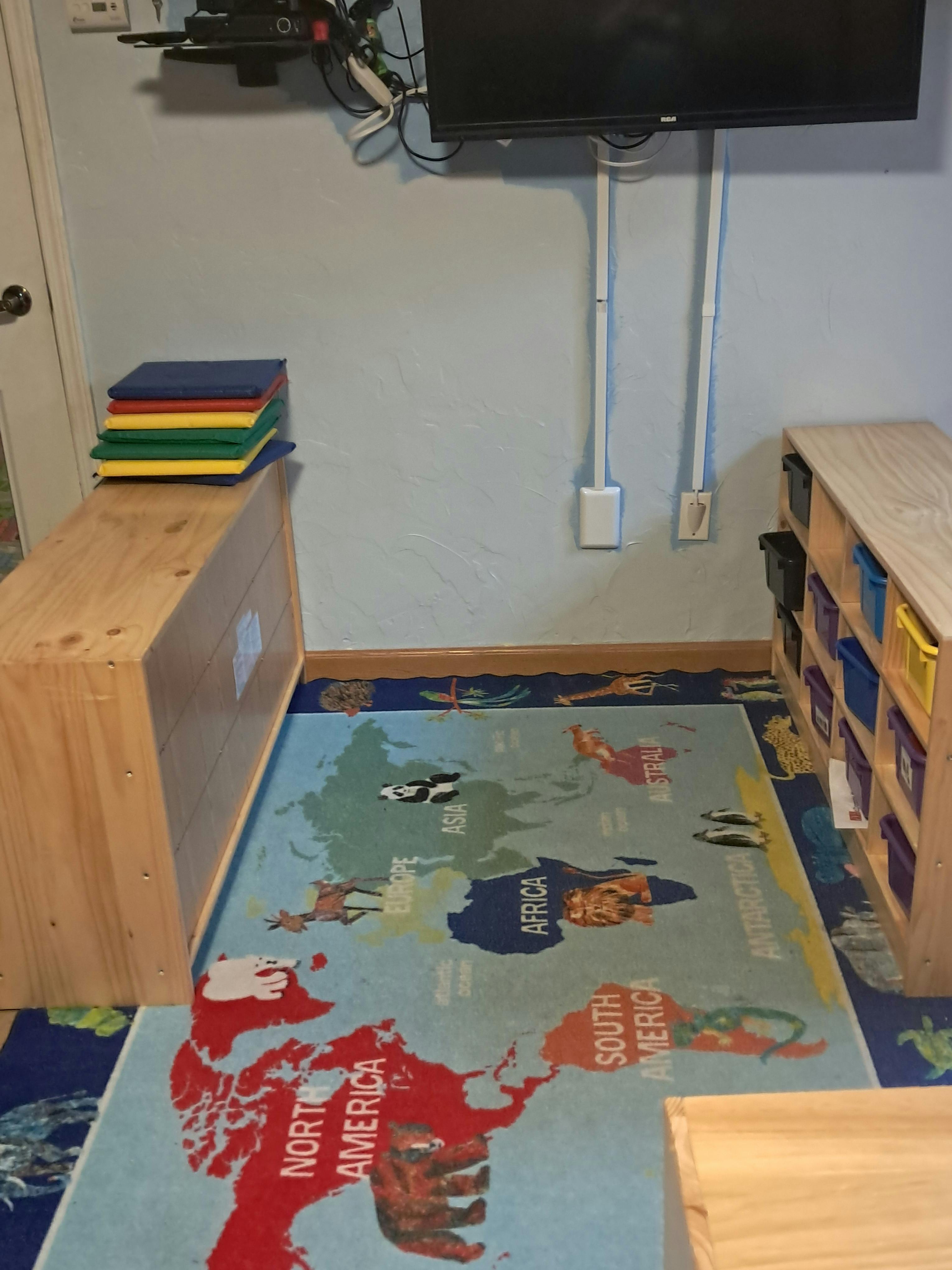 World map rug on the floor with wooden furniture and plastic storage units