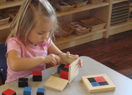 Child playing with wooden blocks and a puzzle on a table