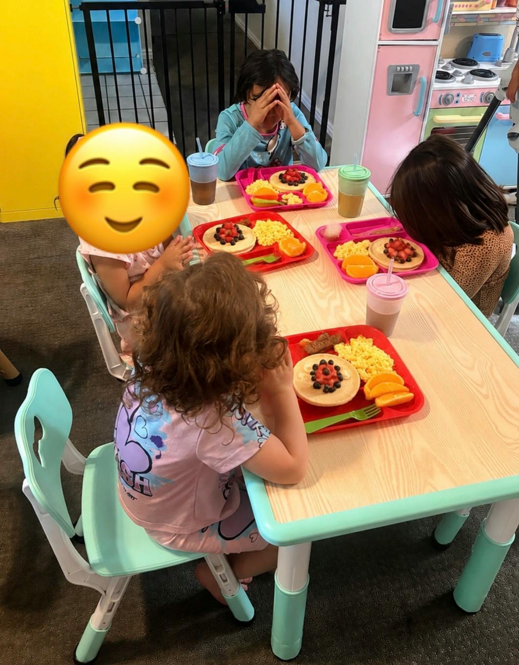 Children sitting at a table with breakfast trays