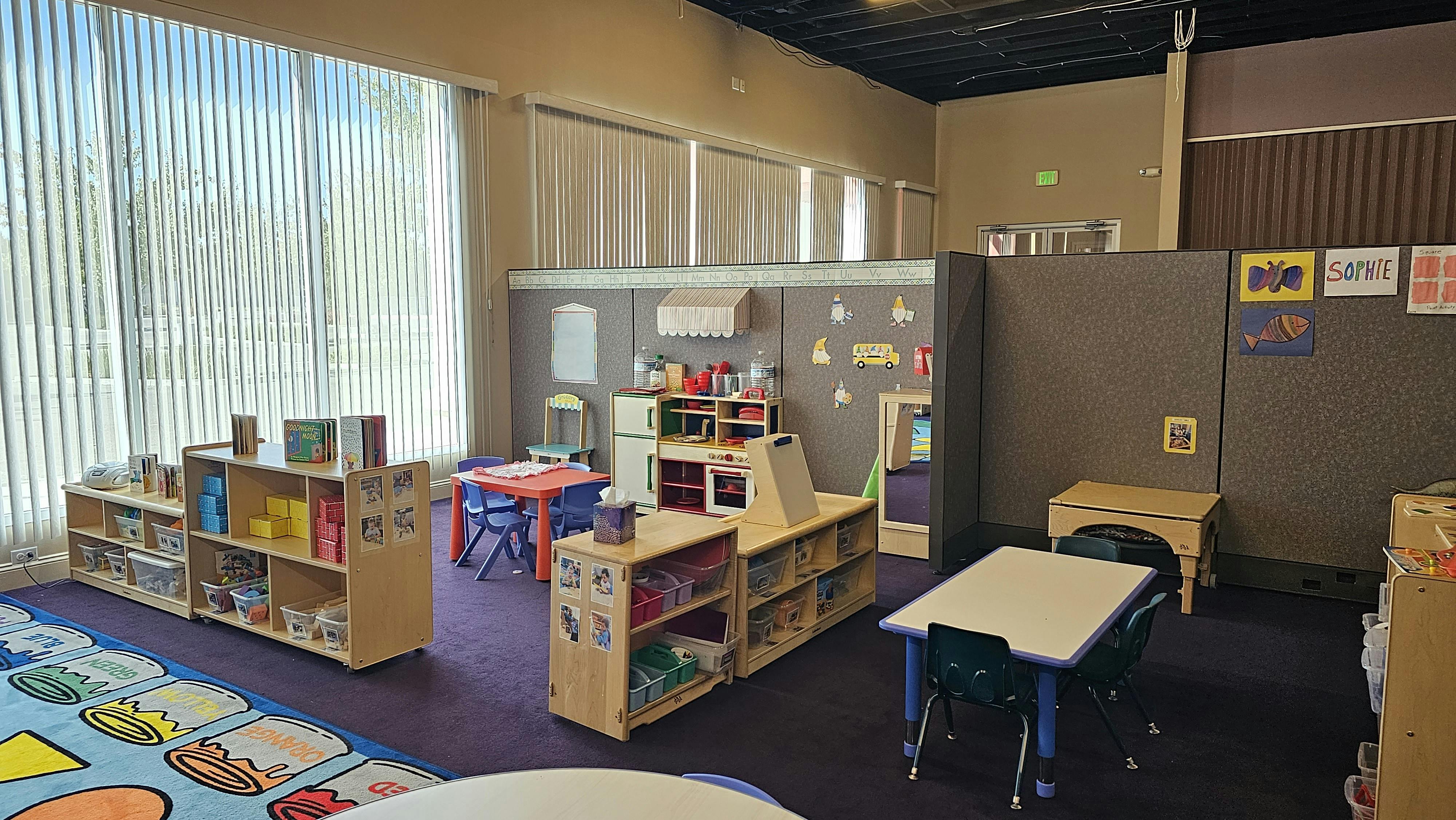 Classroom with small tables, chairs, and shelves with shelves
