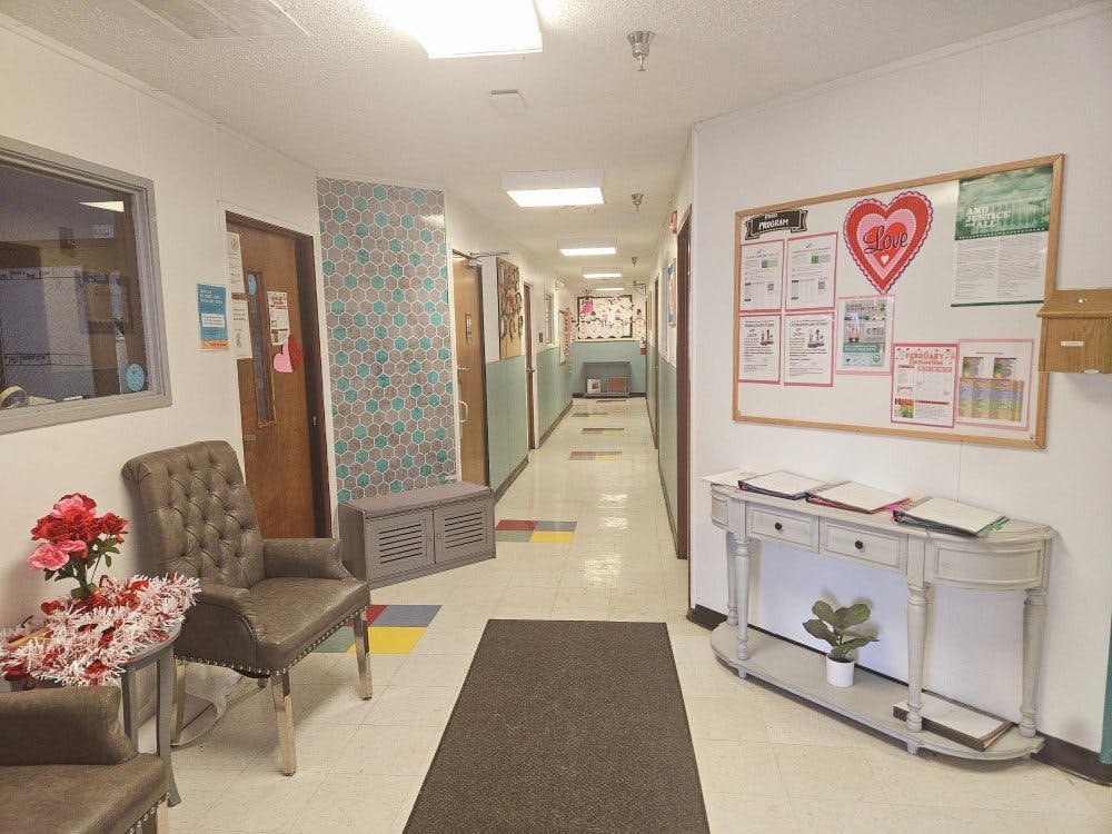 Hallway with chairs, bulletin board, and doors