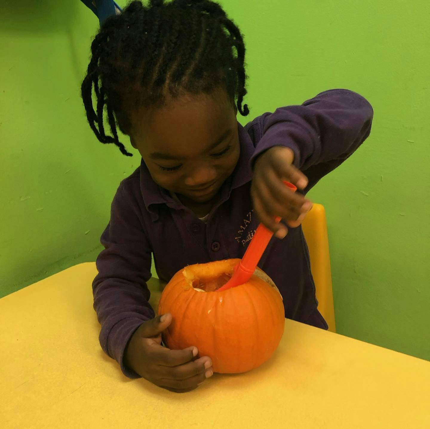 Child scooping out a pumpkin with a spoon