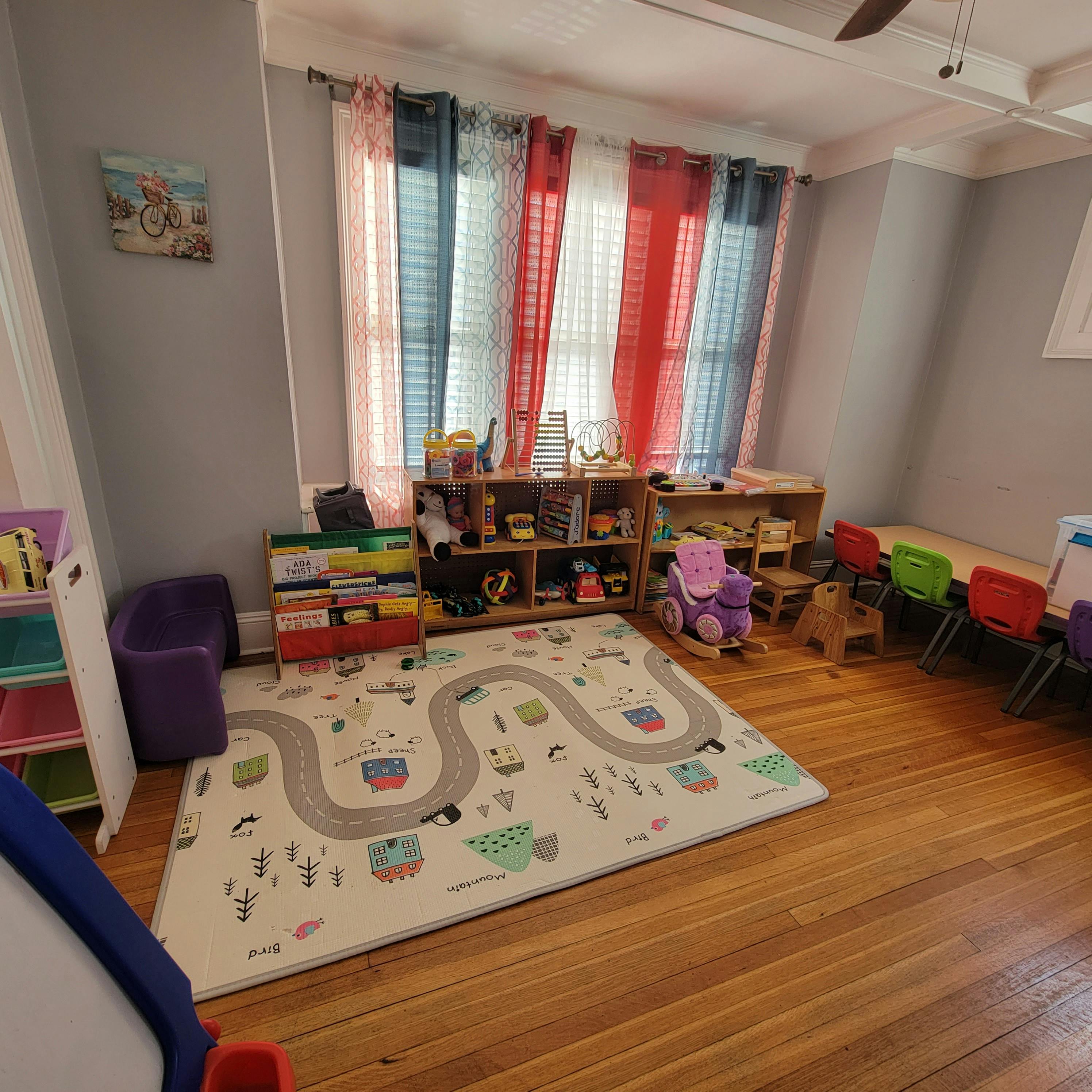 Playroom with a road map rug, shelves of toys, and small chairs