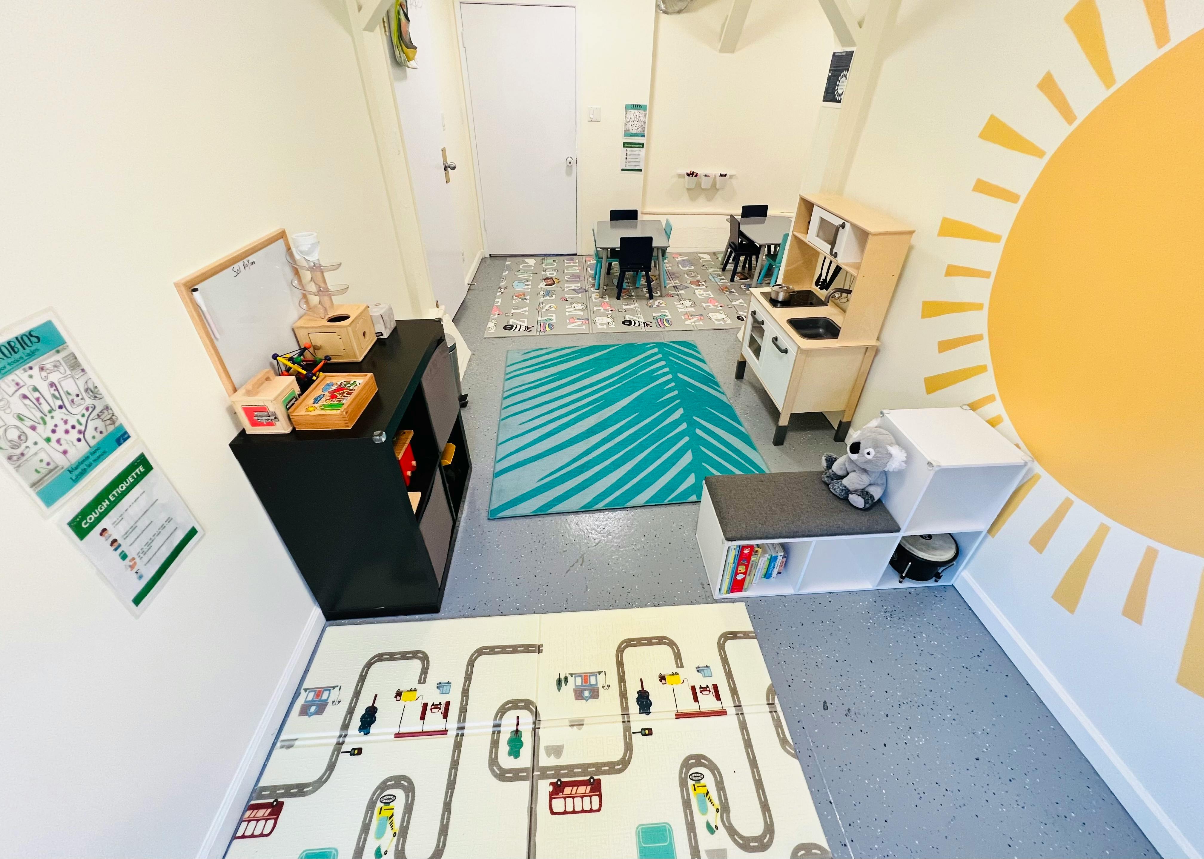 Playroom with a sun mural, play kitchen, and road map mat
