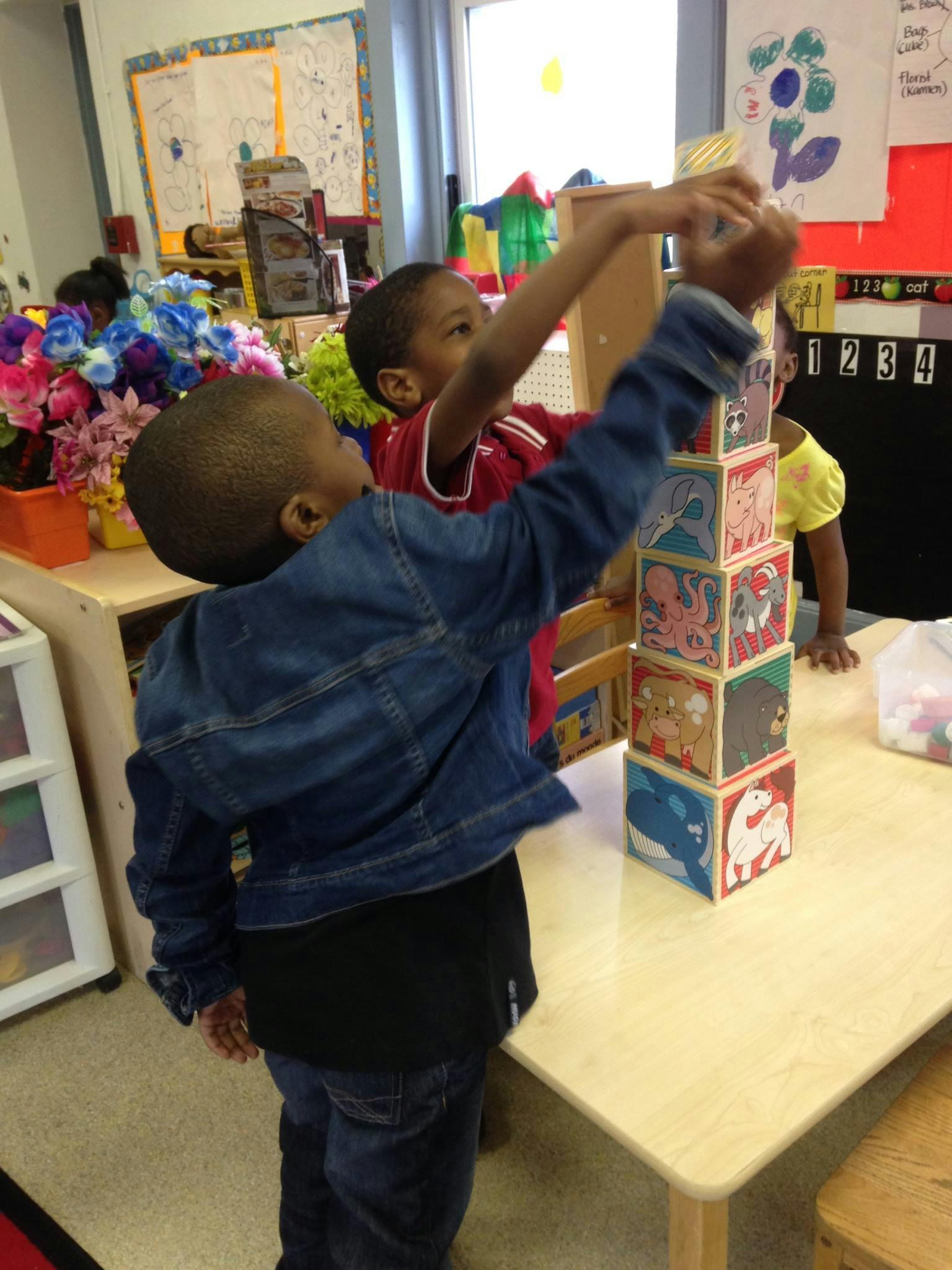 Two children stacking blocks in a classroom