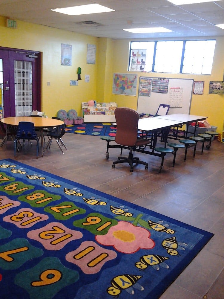 Classroom with tables, chairs, and a colorful rug with numbers