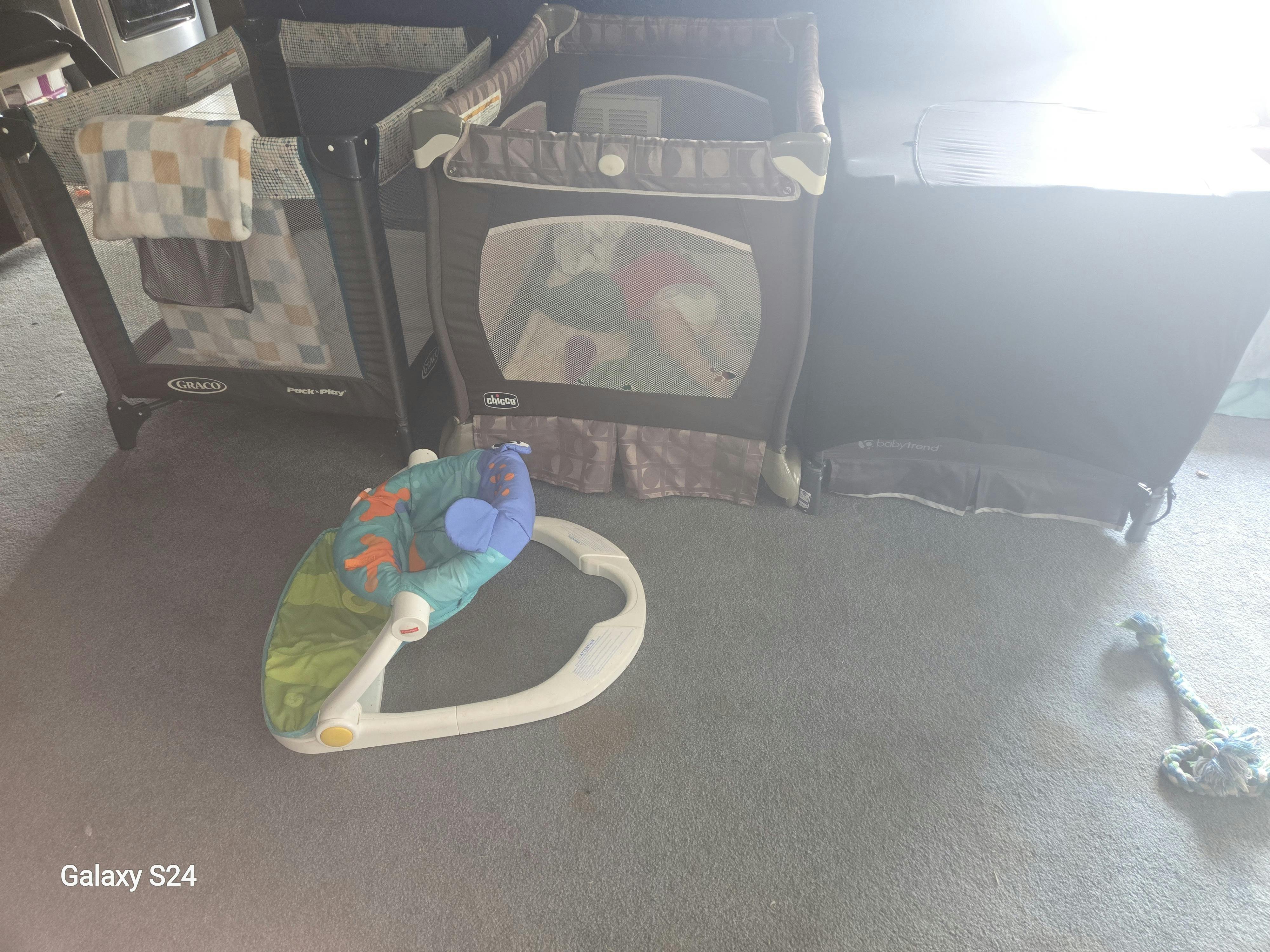 Two portable playards and a baby bouncer on a floor