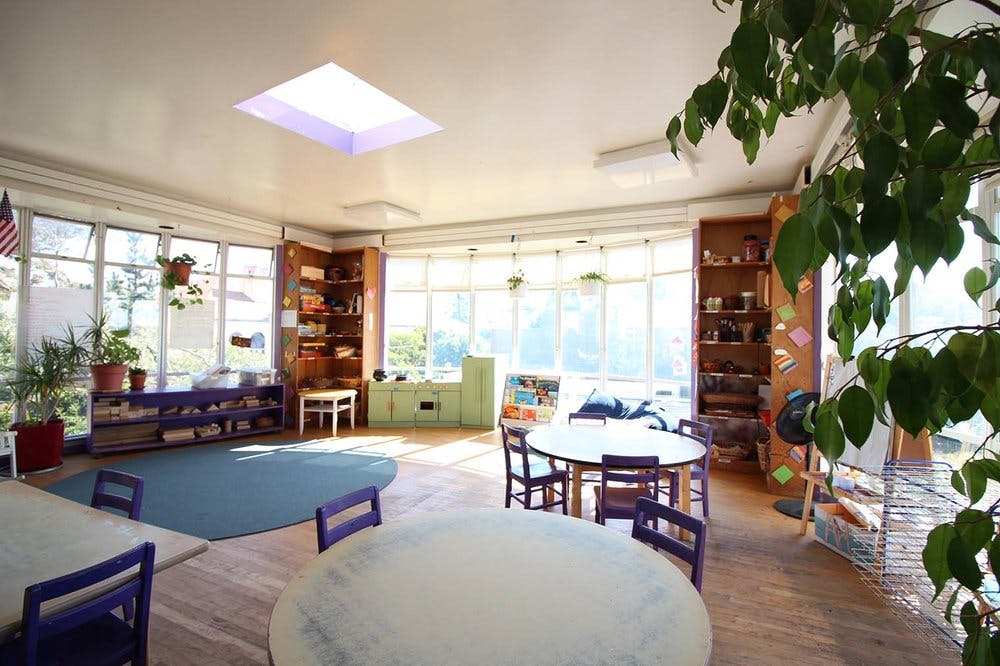 Classroom with tables, chairs, and a blue rug