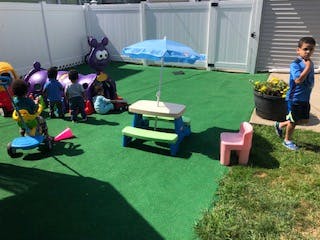 Children playing in a fenced yard with toys and a picnic table