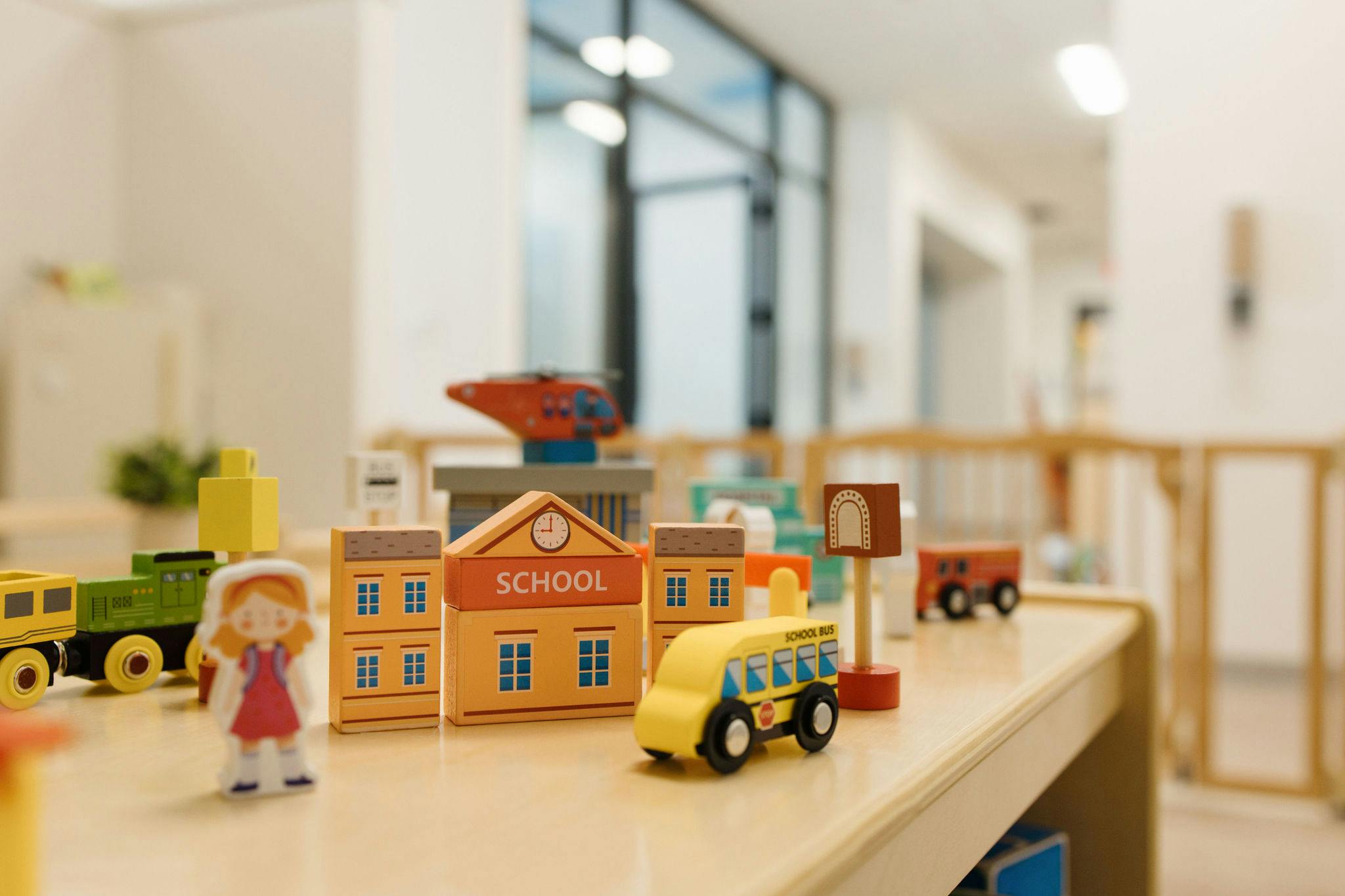 Wooden toy school building and bus on a table