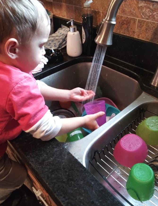 Child playing with water in a kitchen sink