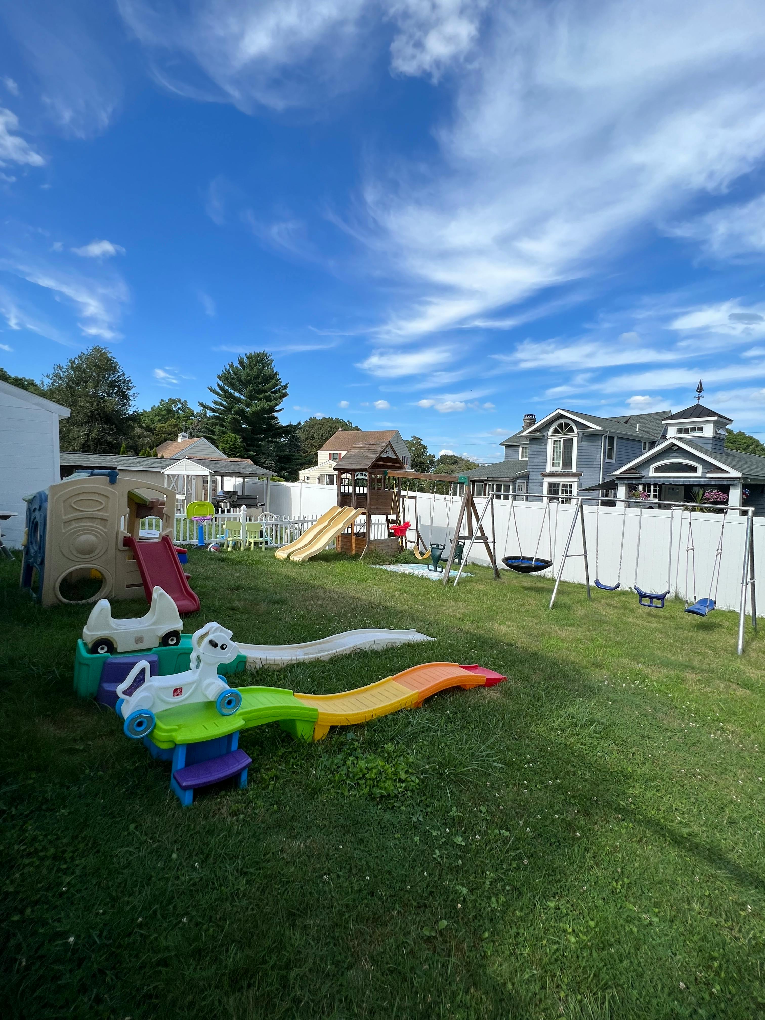 Outdoor playground with slides, swings, and ride-on toys on grass