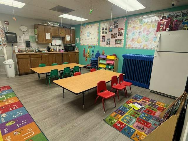 Classroom interior with tables, chairs, and colorful alphabet rugs