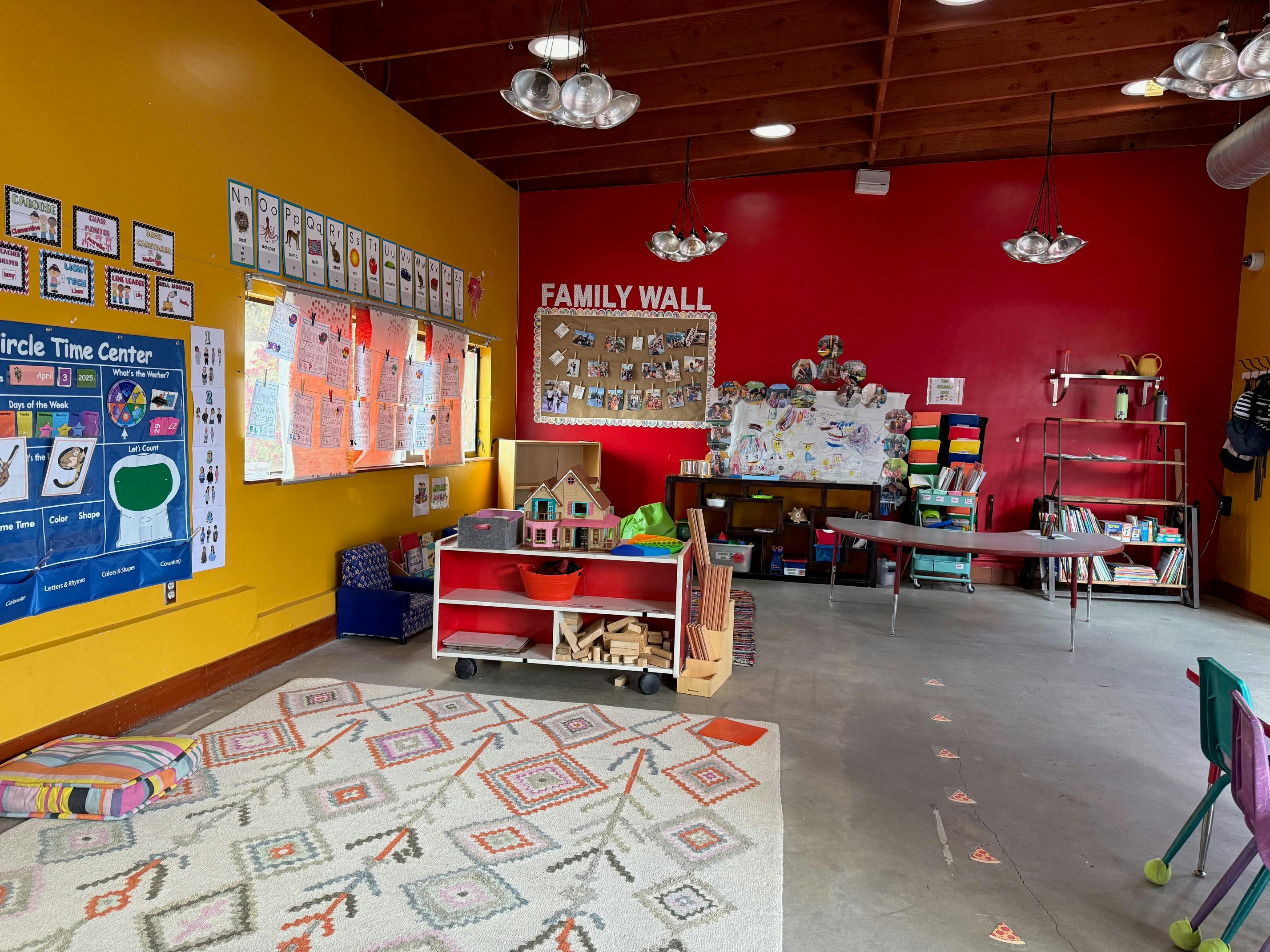 Classroom with yellow and red walls, rug, and learning materials