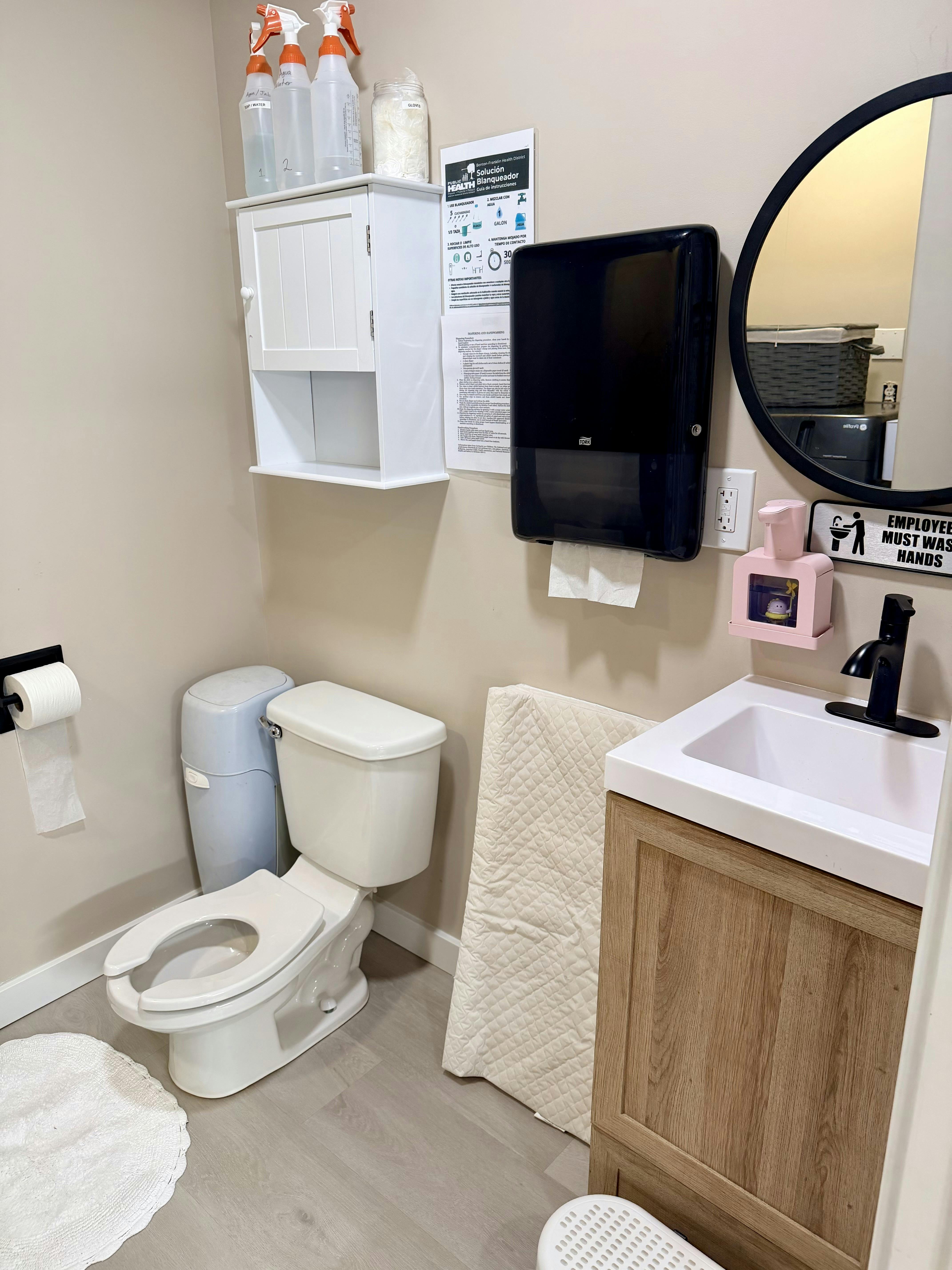 Public restroom with a toilet, sink, paper towel dispenser, and signage