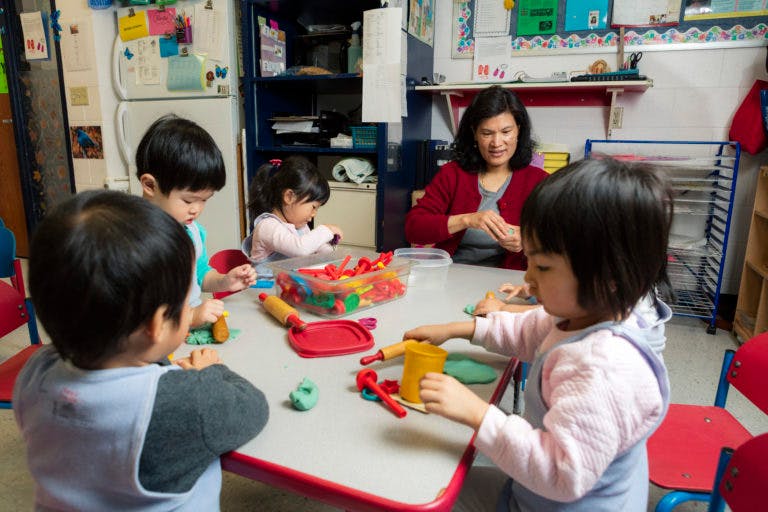 Adult and three children playing with modeling clay at a table