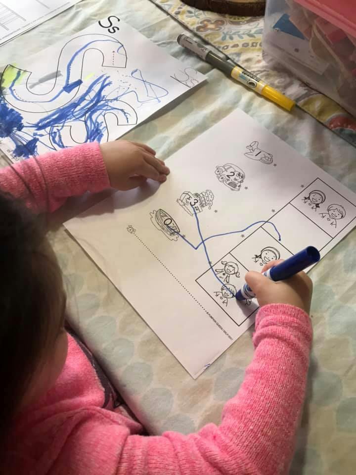 Child drawing on paper with a blue marker