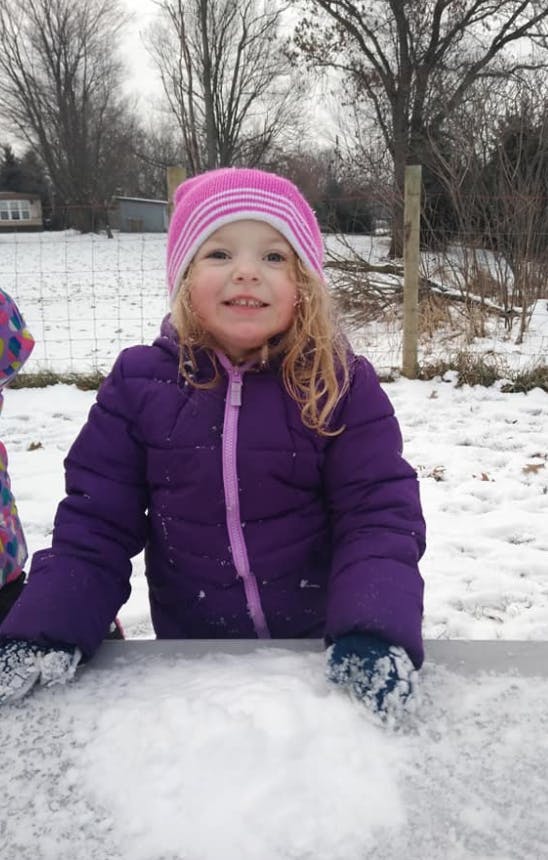 Child in winter coat and hat playing in snow
