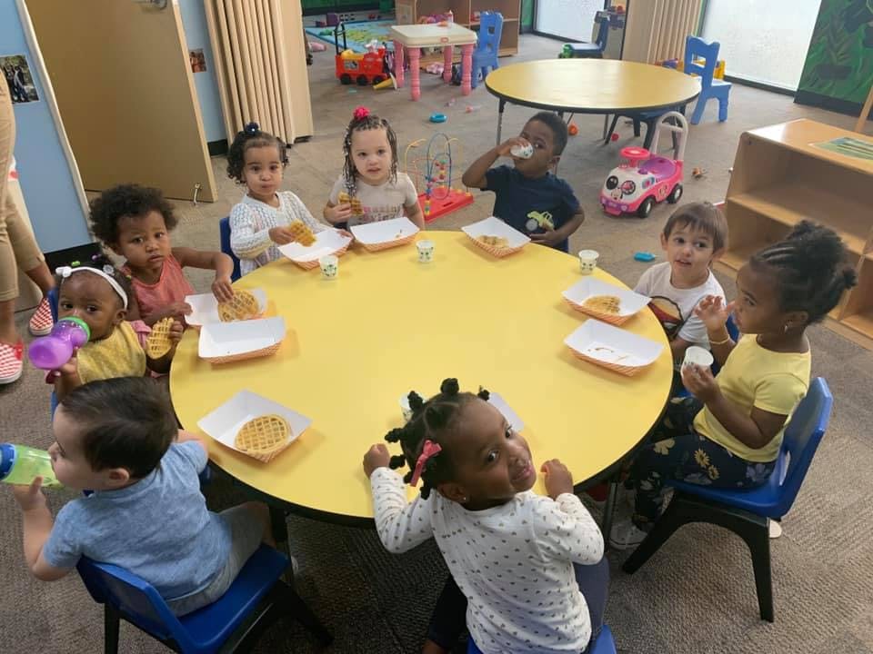Children sitting around a yellow table with plates