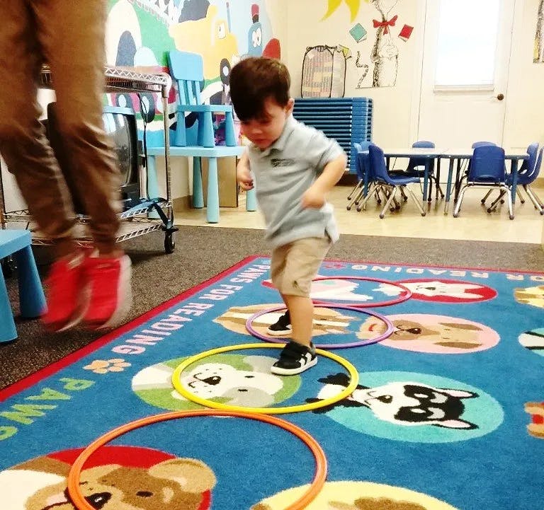 Child playing with hoops on a rug in a classroom