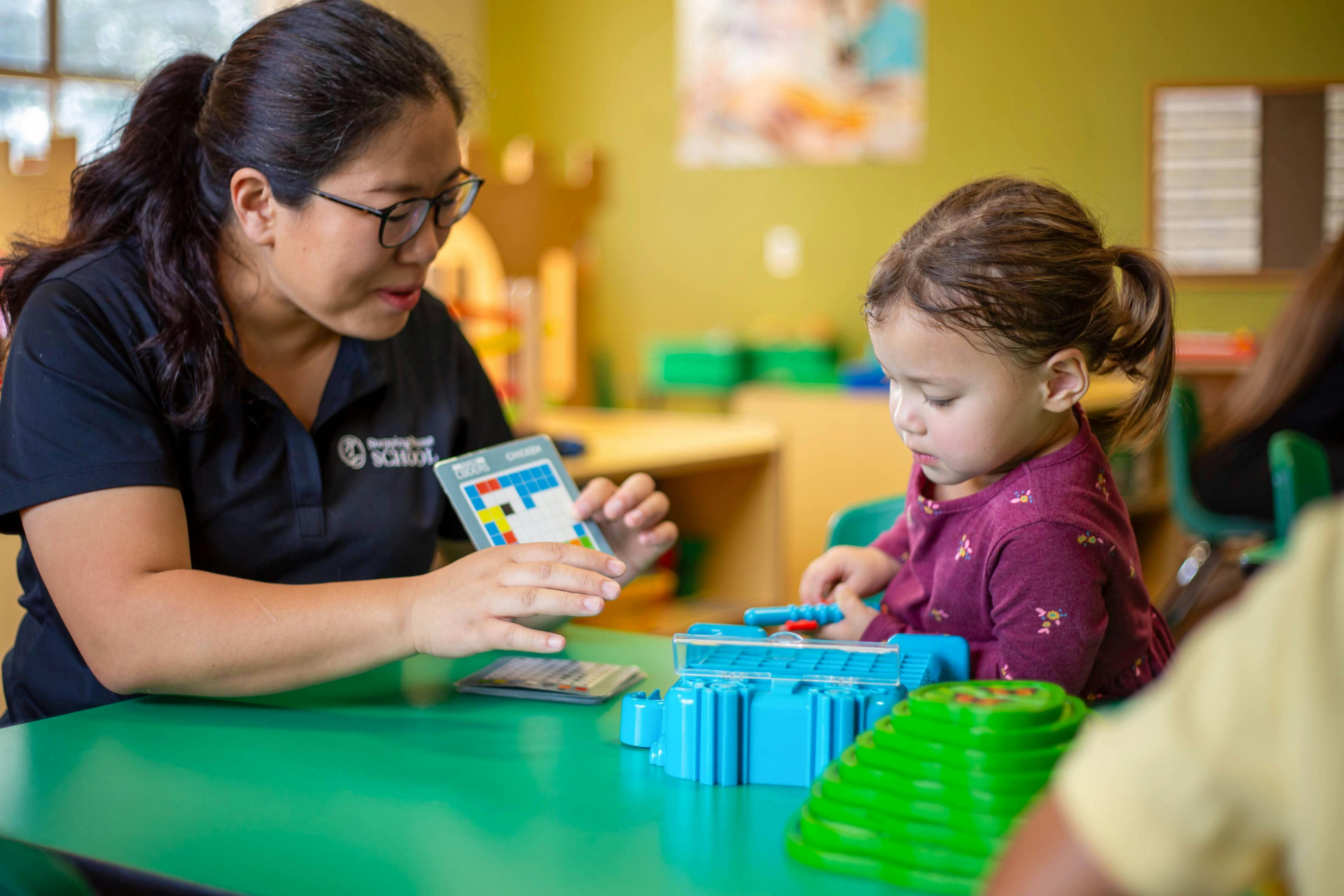 Person holding a game card next to a child playing with a toy