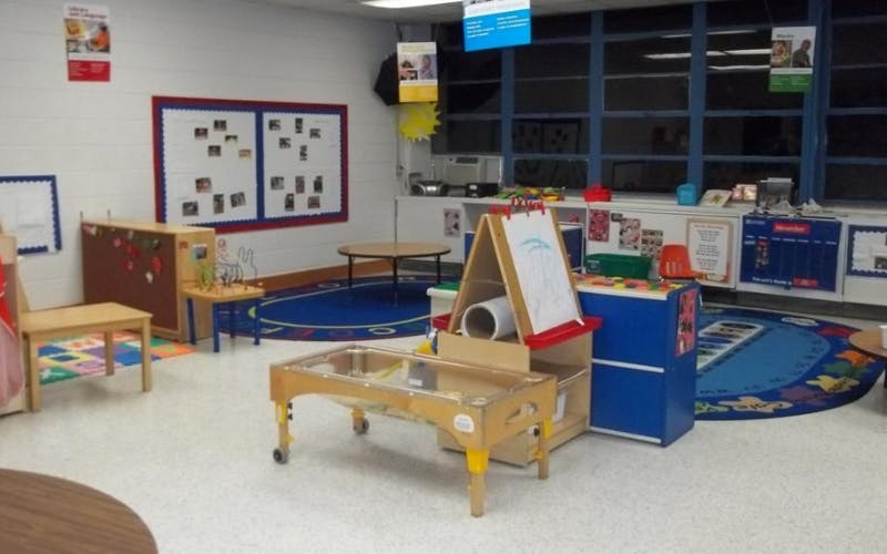 Classroom with various learning stations, small tables, and a blue rug