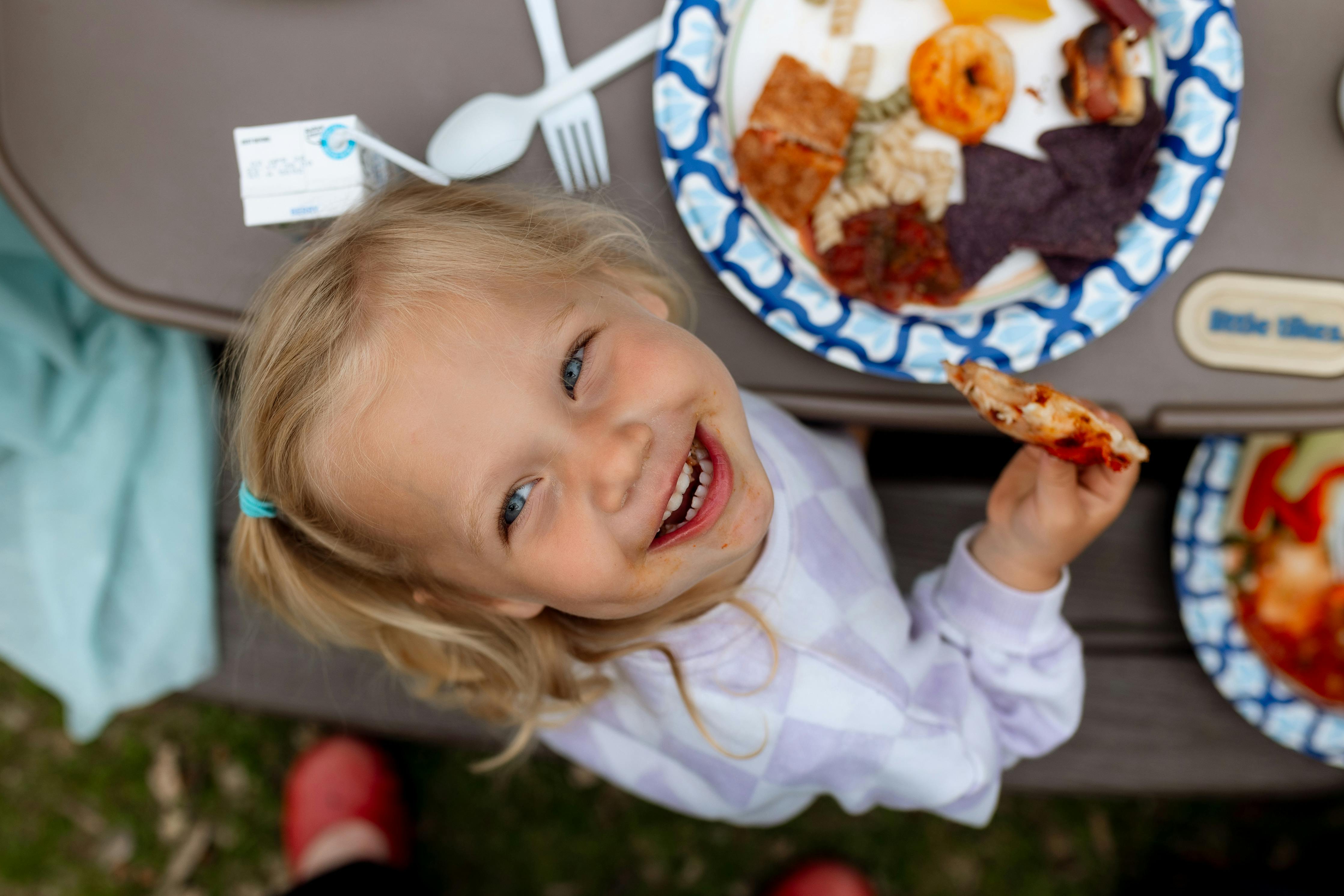 Child holding a piece of food at a table