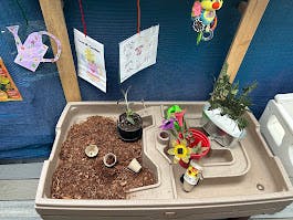 Sensory table with soil, plants, and small toys