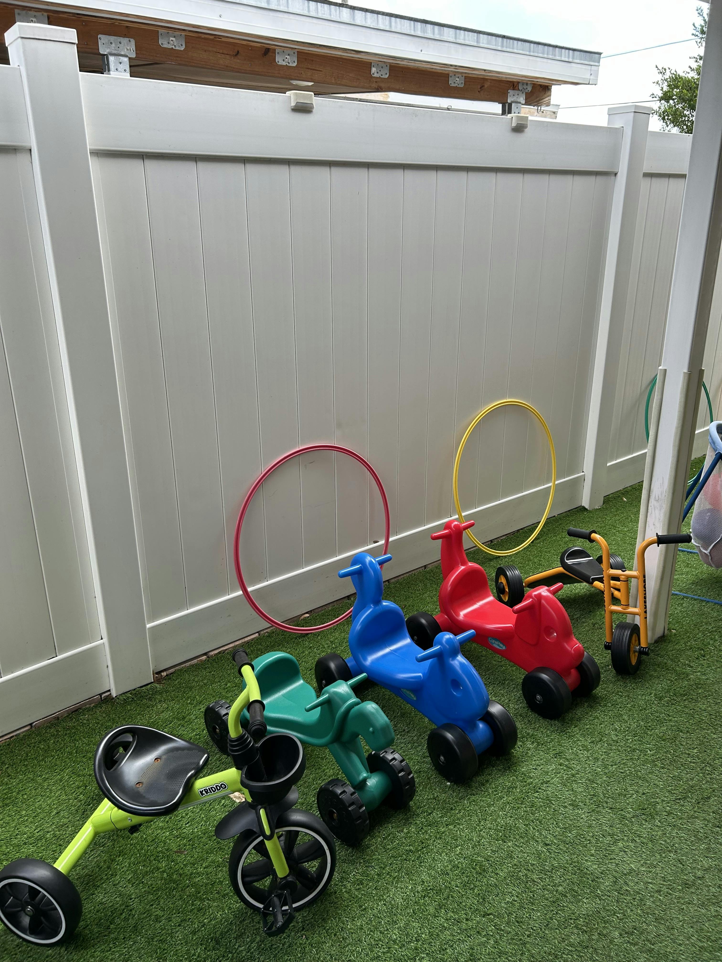 Several tricycles and ride-on toys on green artificial turf