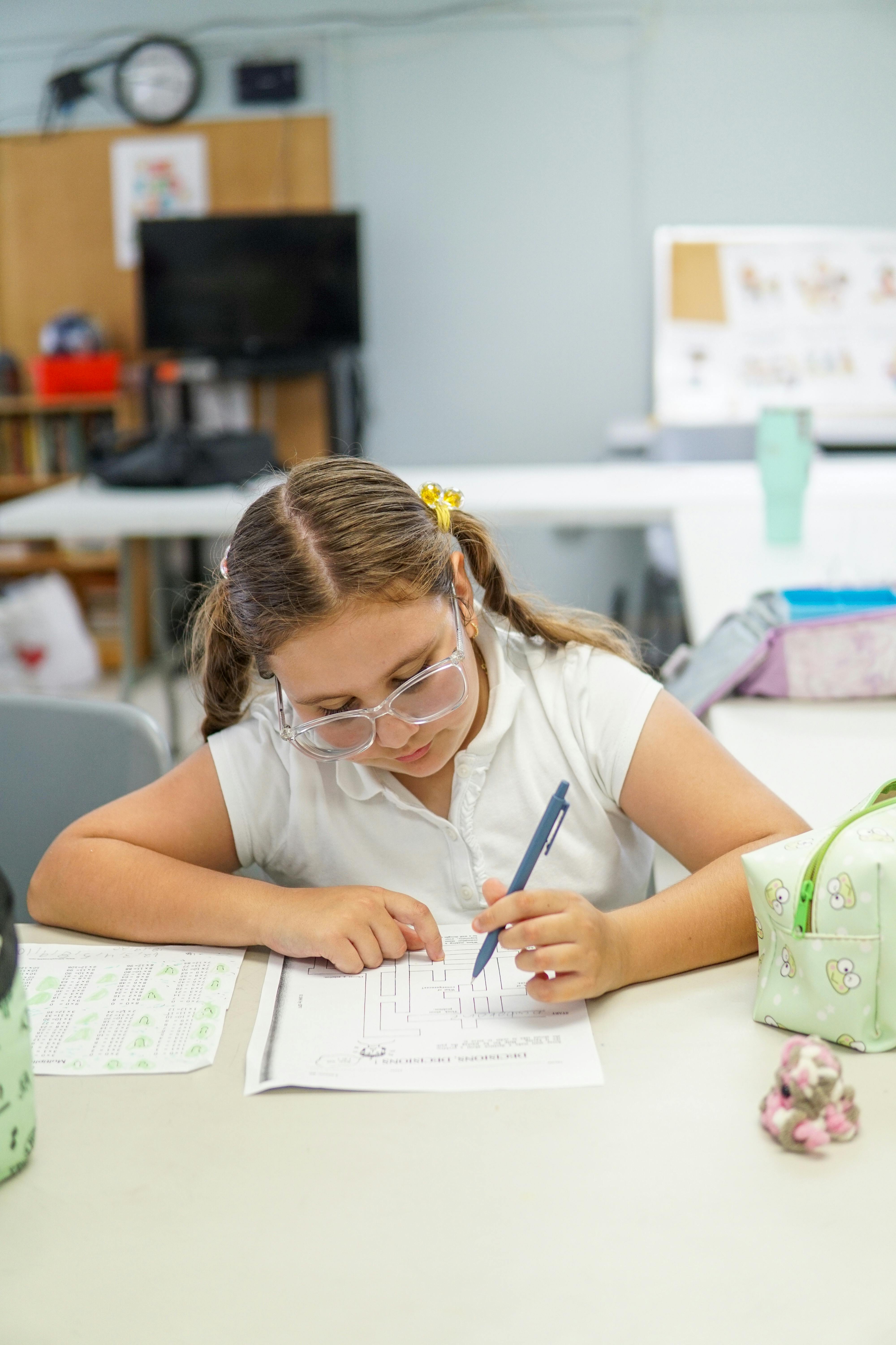 Child working on a worksheet at a desk in a classroom