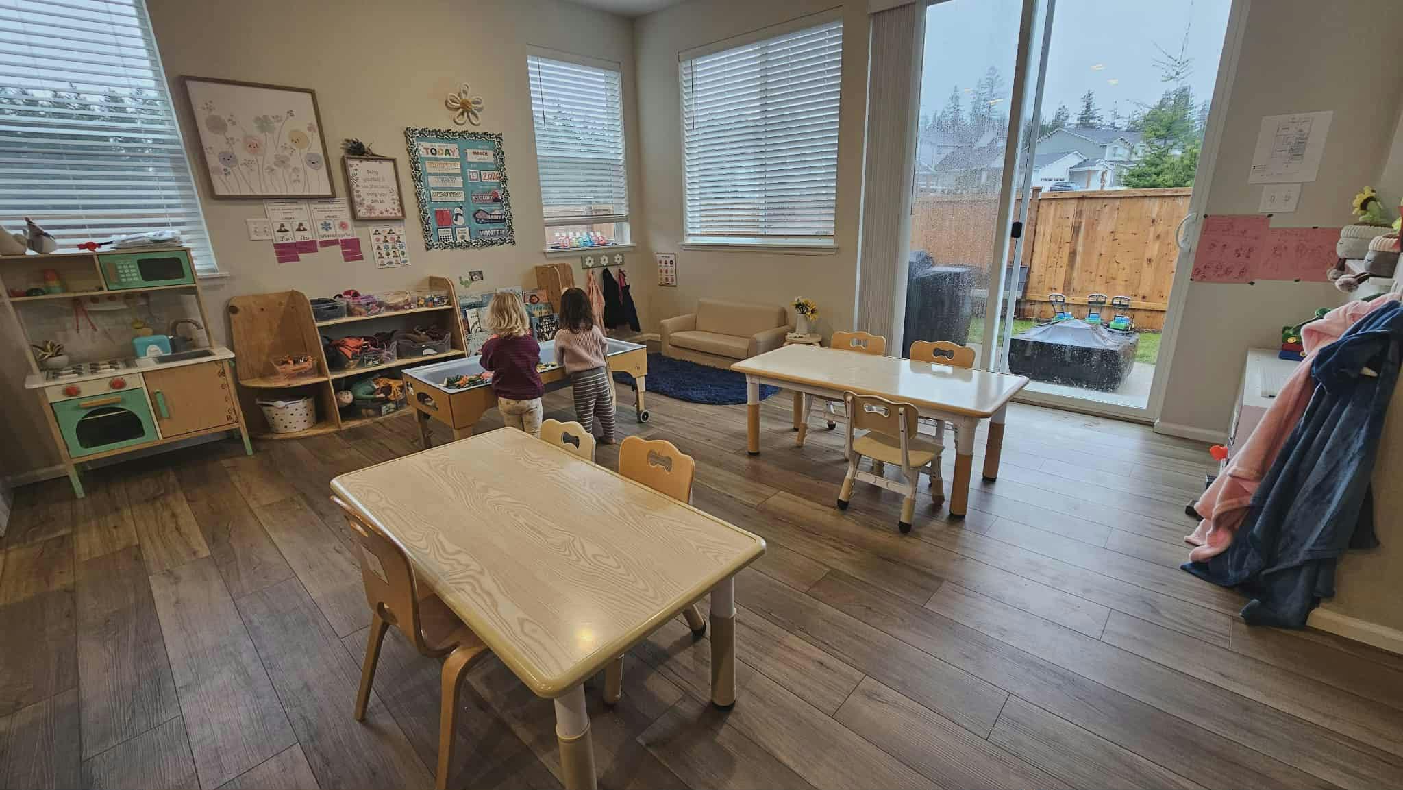 Two young children playing together at a sand table in a classroom