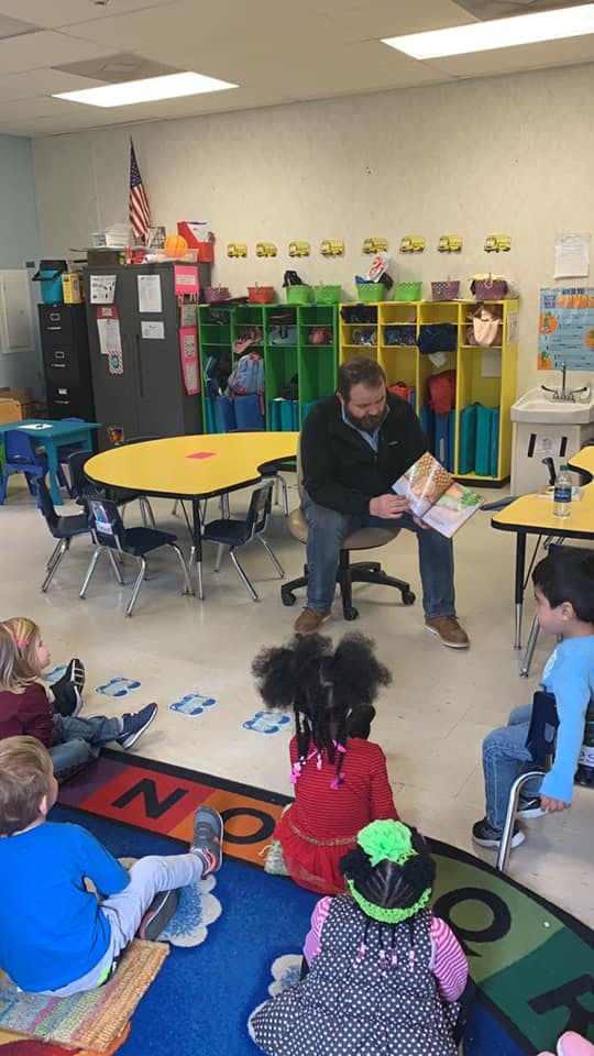 Adult reading a book to children in a classroom