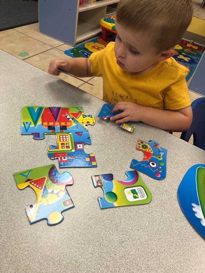 Child playing with puzzle pieces on a table