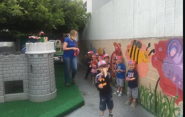 Adult and children standing near a wall with painted murals